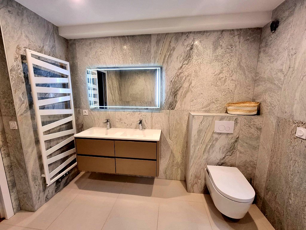 Même salle de bains vue de l'autre côté : double vasque suspendue, WC suspendu et sèche-serviettes.